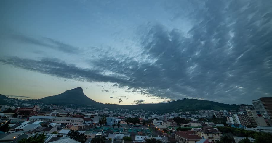 Clouds pass over residential neighborhoods as sunset turns into night