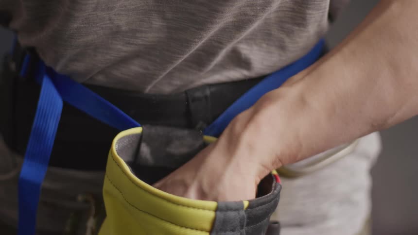A man reaches his hand into a chalk bag used for climbing