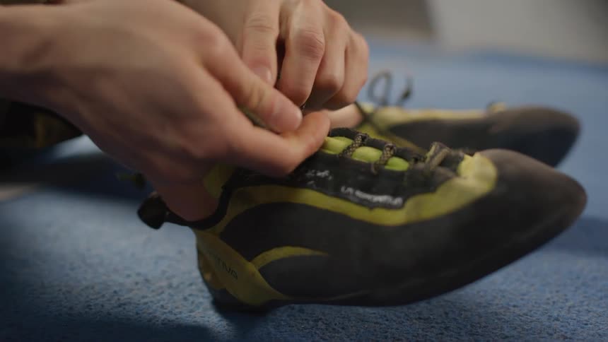 A woman ties on her shoes in preparation to climb