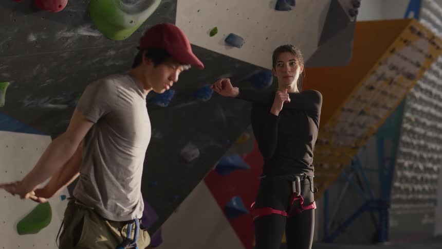A man and a woman stretching in an indoor climbing gym