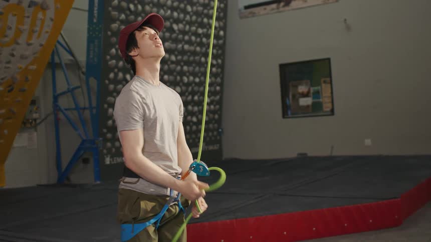 A man in a gym pulling on a security climbing rope attached to his belt