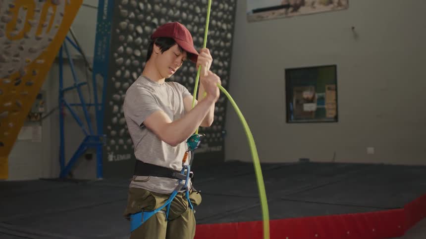 Young man tightening a safety harness with a climbing rope