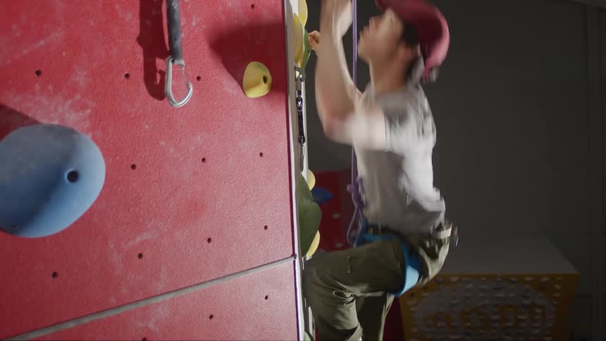 Man climbing an indoor climbing wall in a harness