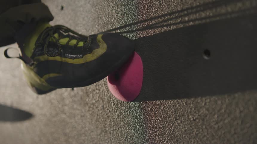 A person's foot finding a hold on a fake climbing wall