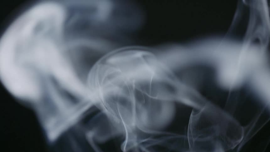Extreme closeup of white smoke rising on black background