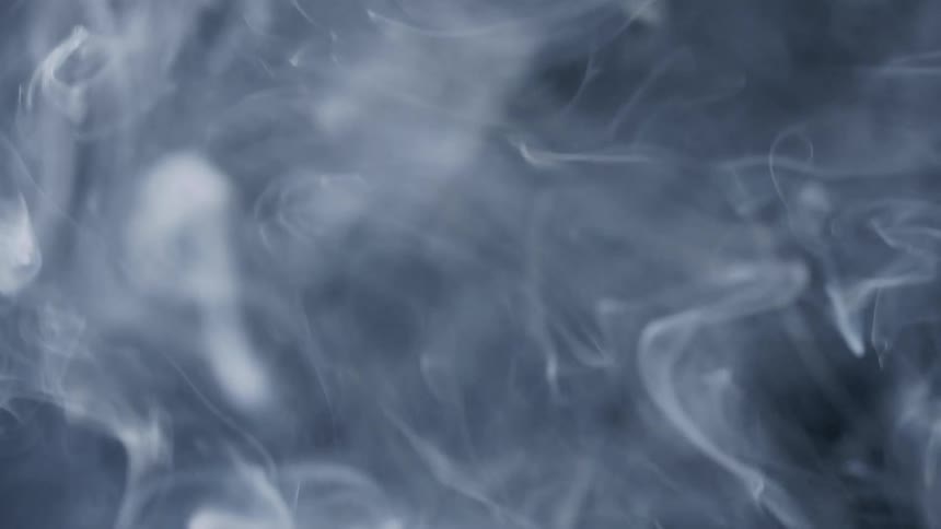 Smoke continuously rises into the air in a dark environment