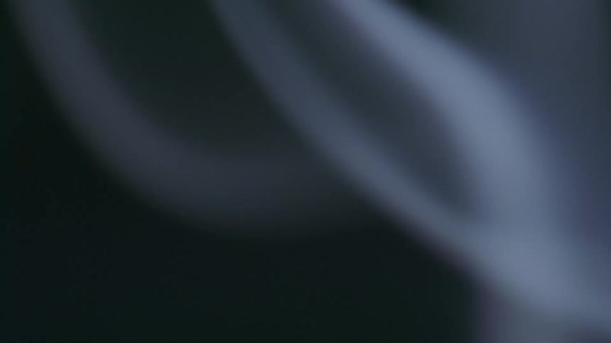 Extreme closeup on whitish smoke rising on a black background