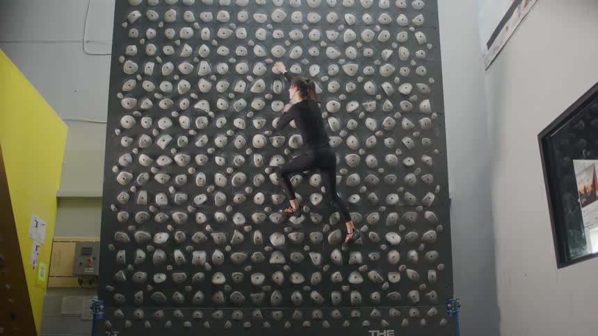 Woman training with a variety of hand holds on a kilter board climbing wall