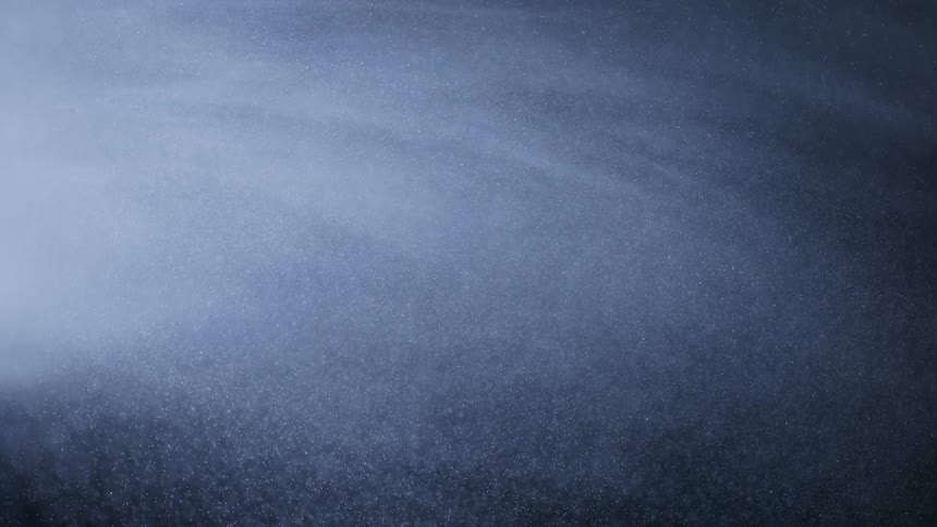 Numerous brighted colored particles slowly drift through the darkness