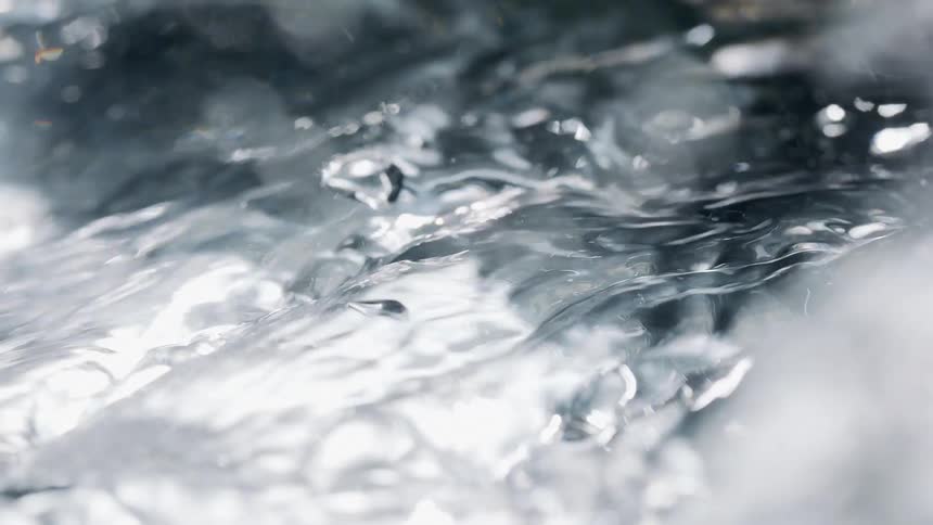 Extreme closeup on crystal clear water with bubbles and drops moving abstractly