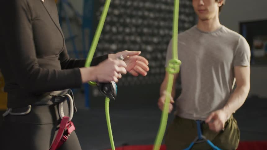 A man and a woman grab a hanging safety rope for wall climbing