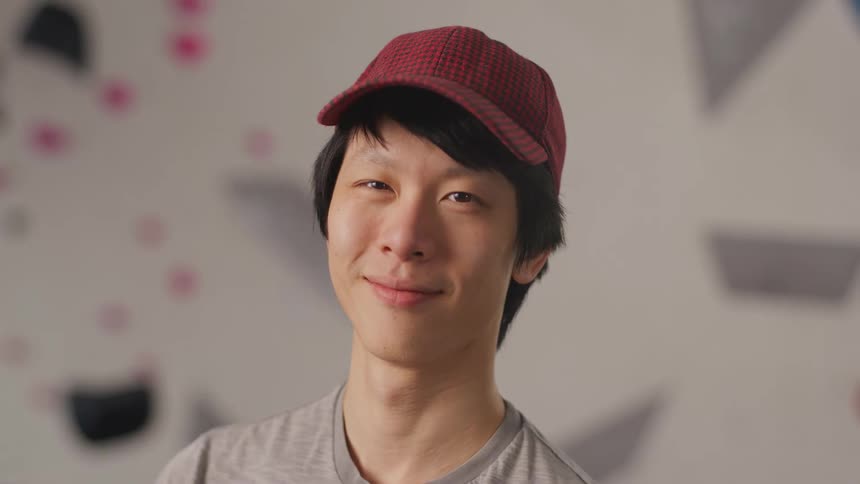 A young asian man turns his head and smiles