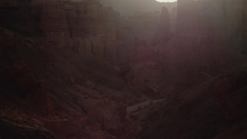 A view of a large canyon with the sun in the distance