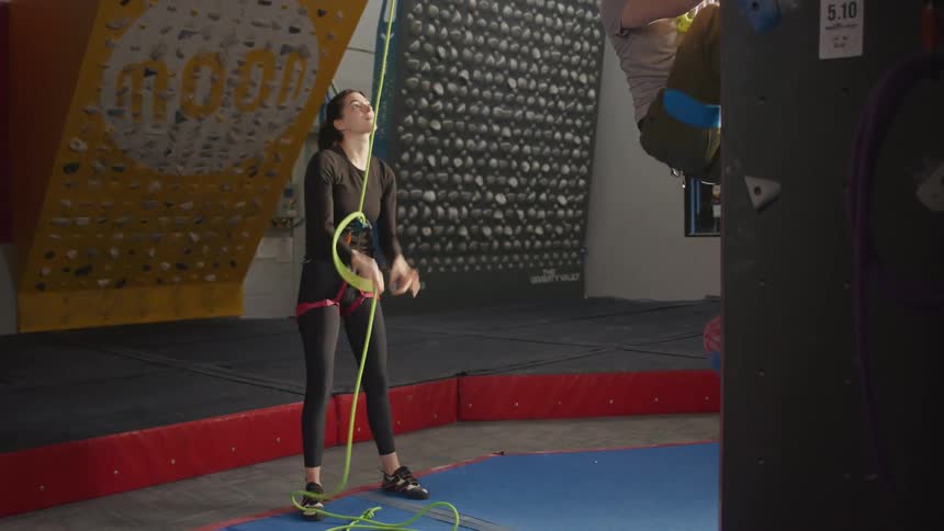 A man climbs a wall while a woman supports from below
