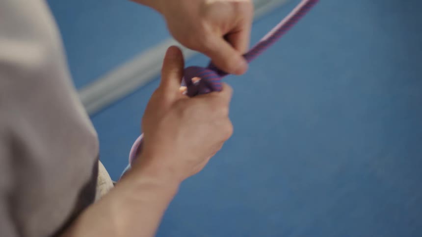 A man tying a safety rope to his belt with many large knots