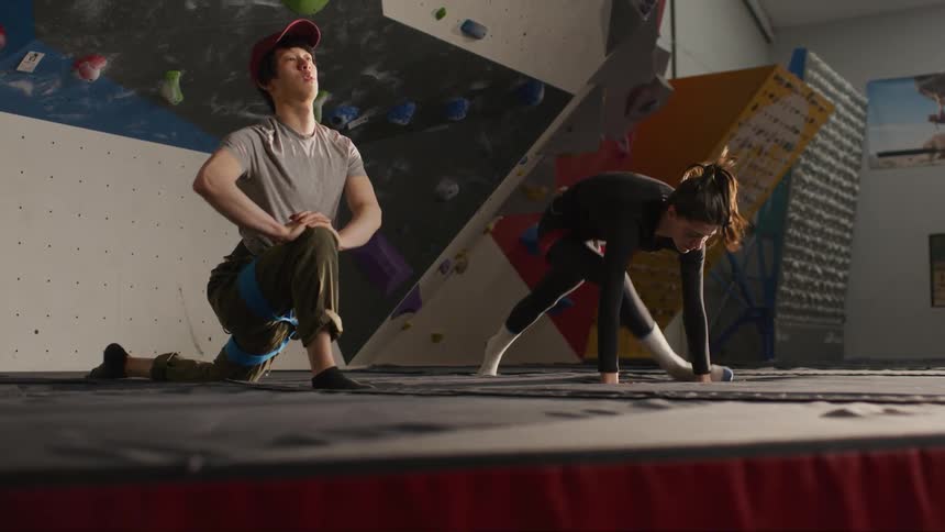 Man and woman stretching their bodies in preparation for indoor climbing