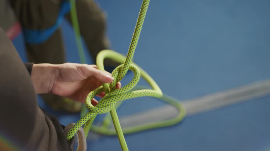 Hands of a woman tying a rope on her climbing equipment