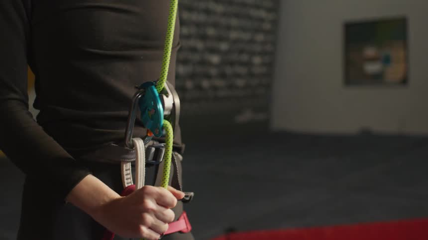 A woman tightening the rope for the climbing harness at her waist