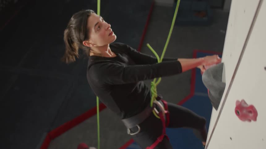 Woman climbing a fake climbing wall with a safety belt