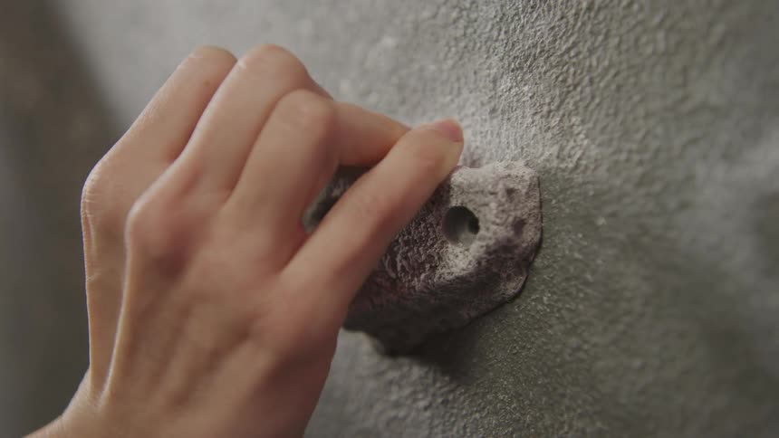 A hand grips a handhold on a climbing wall