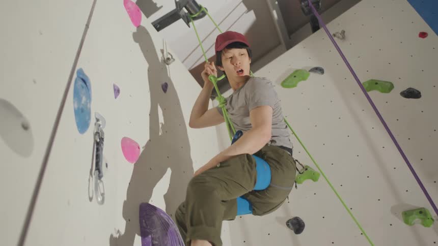 A man climber is descending a rope from the top of a wall he climbed