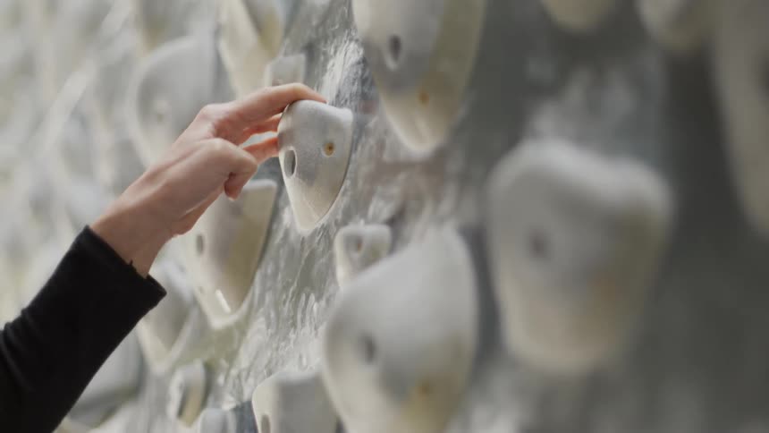 Hand and legs of a woman training on a climbing wall