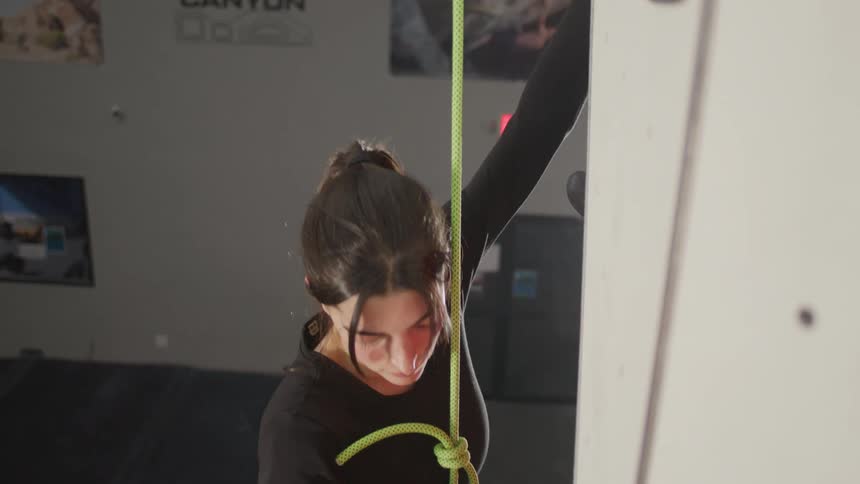 A young woman climbing a wall in a climbing gym