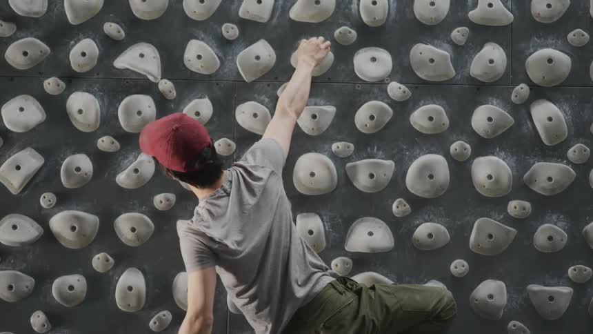 An man climbs a kilter board wall at a climbing gym