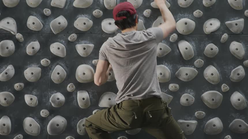 A man climbs down a kilter board climbing wall