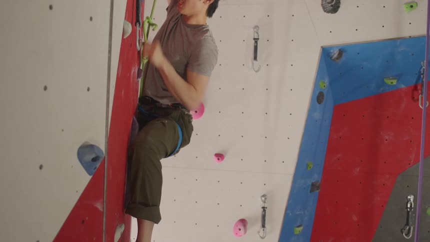 An asian man climbs in a climbing gym