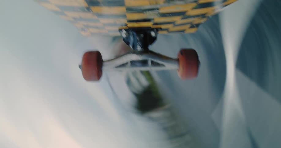 A skateboard is spinning in the air and on the ground there is an asphalt surface