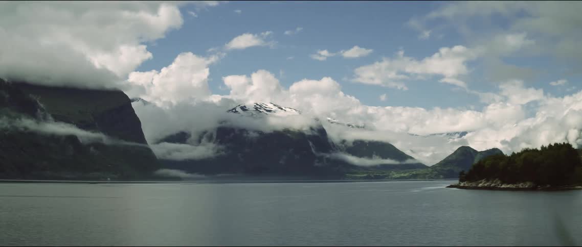 Timelapse landscape of the sea surrounded by snowy mountains during the day
