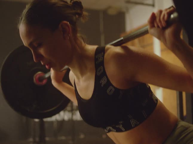 Concentrated woman doing squats on free bar with weight