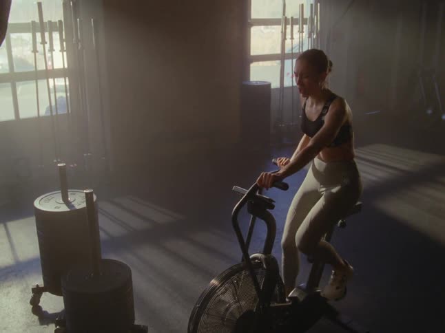 A woman finishes exercising on a bike in a gym
