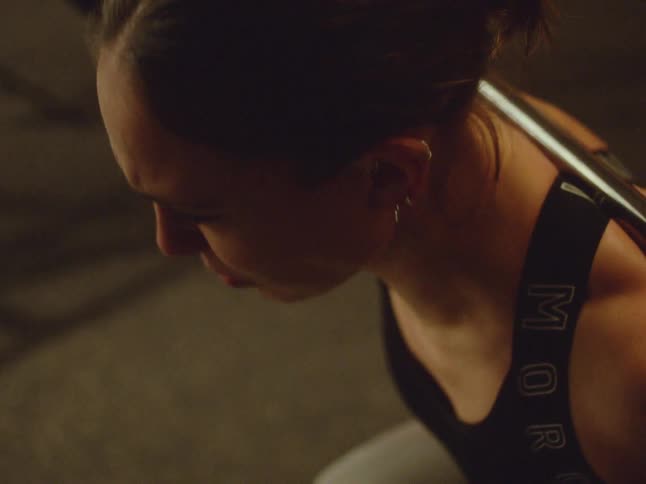 Woman exercising in gym sweats while lifting weights