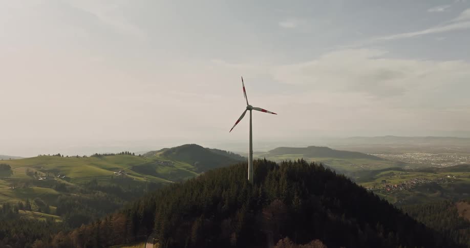An aerial view of a wind turbine in the middle of a forest