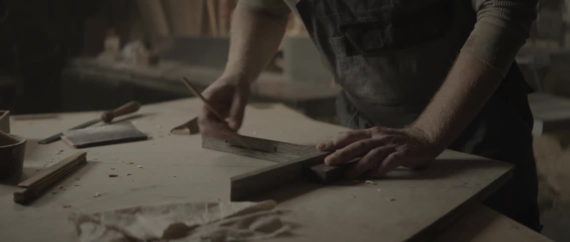Hands of a carpenter man with the help of a pencil measuring and scribbling a baby bottle