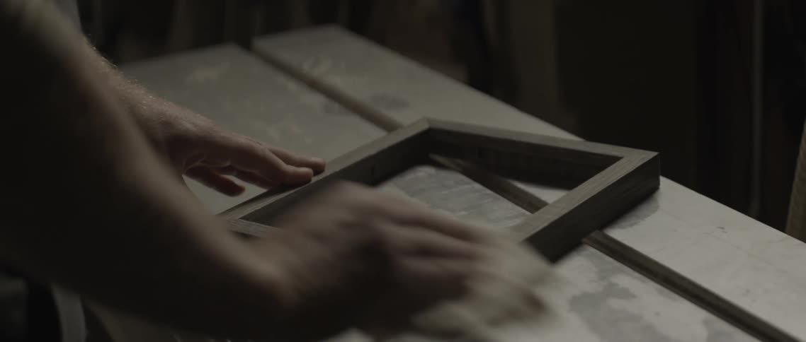 A man polishes a wooden frame