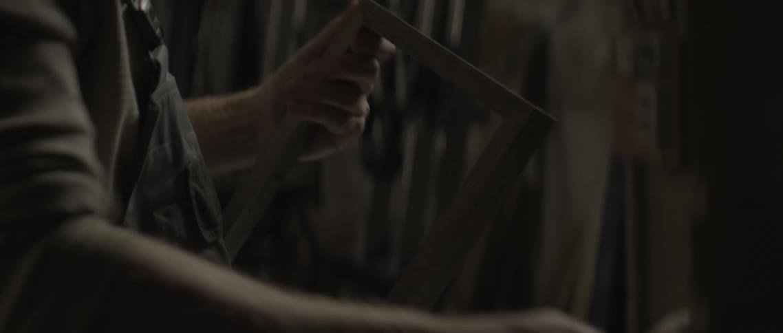 Hands of a carpenter cleaning and sanding a wooden frame