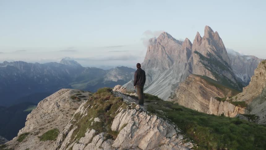 Man standing on edge of moutain peak looking across to the canyons