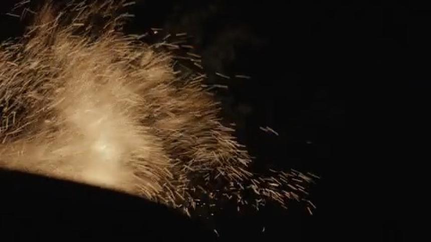 Sparks and embers are released upwards into the night sky