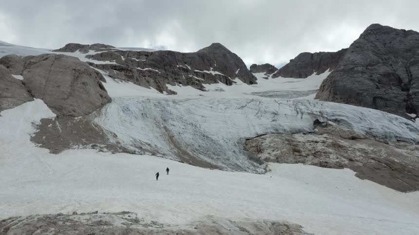 Natural scenery of rocky mountains with snow and two people hiking