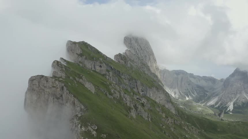 Scenery of greenish and rocky mountains with fog around