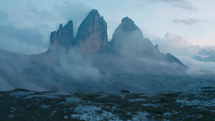 A hiker walking across a plateau thats part of a mountain range