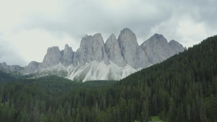 Scenery like a nicotine forest on hills and in the background giant mountains with cliffs on a cloudy day