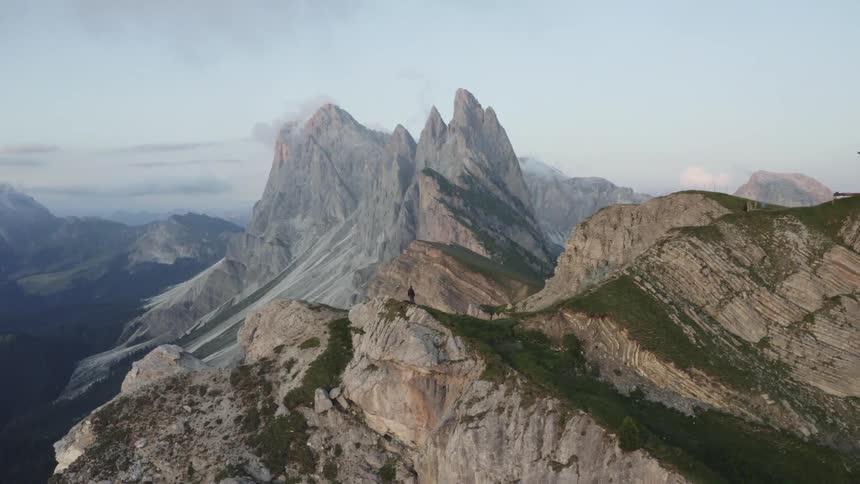 A person and a large cross on top of a massive mountain range