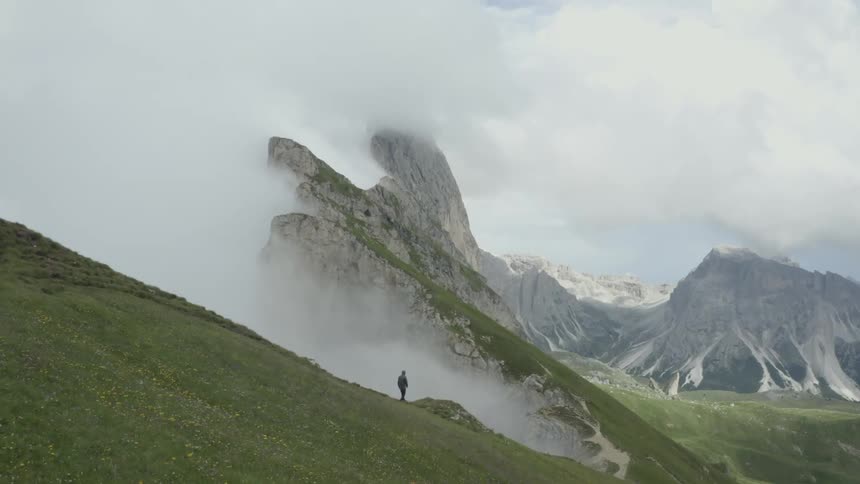 A person walks along a cavernous whole in the side of a mountain