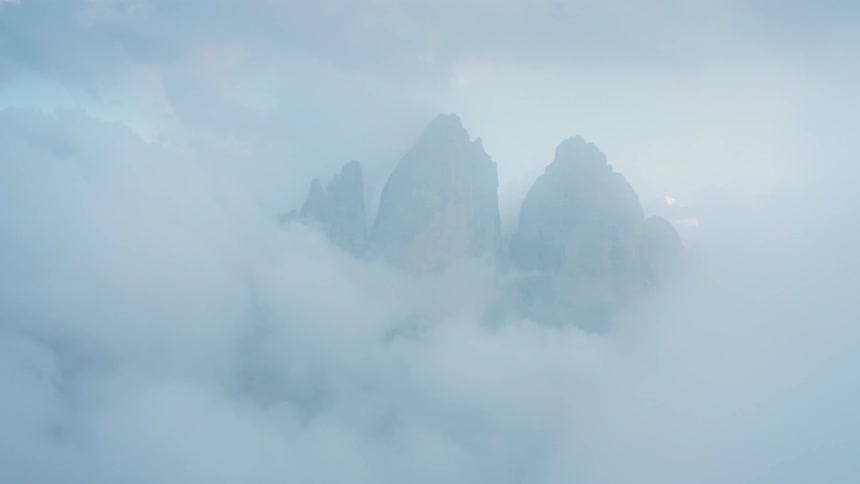 Scenery with rocky mountain cliff peaks with clouds around in a morning