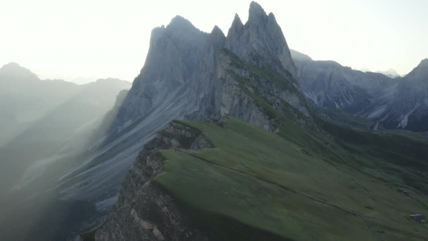 A hiker walks down a trail at the top of a mountain range on a clear day
