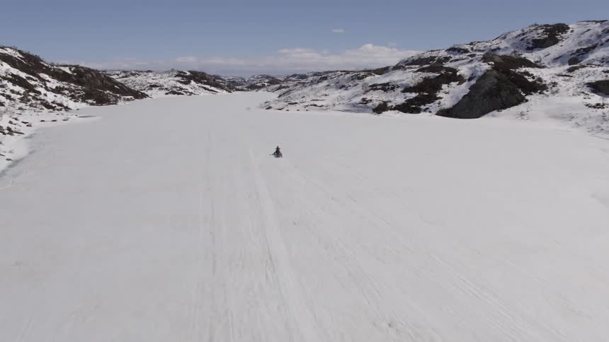 Person exiting snowmobile through snow with mountains around